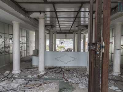 Siamo ora nell'ambiente in cui era probabilmente attiva la reception: qui � rimasto il tavolo celeste fissato al pavimento dove presumibilmente venivano accolti i clienti, circondato da una serie di vetrate imbrattate da alcune scritte